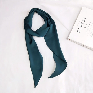 Macro shot of dark green silk scarf on white fabric next to a lifestyle magazine