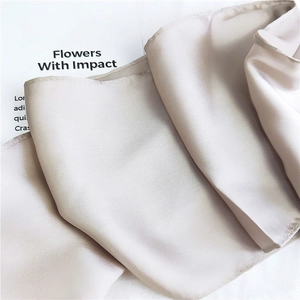 Macro view of champagne silk scarf showing smooth satin texture and fine edge stitching