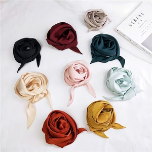 Elegant silk-like satin scarves in nine solid colors styled as roses on a white backdrop