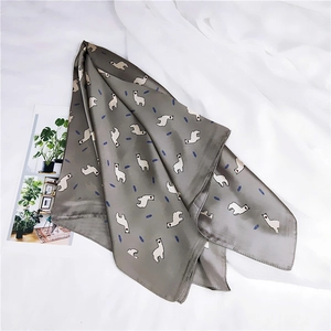 Gros plan d'un foulard en soie avec imprimé alpaga et feuilles sur tissu gris et tulle