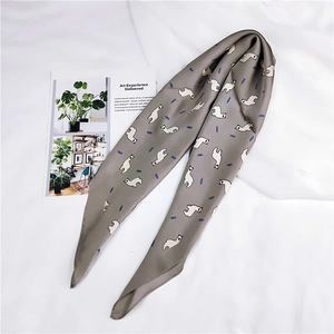 Détail d'un foulard gris en soie avec motifs d'alpagas blancs et de plumes bleues