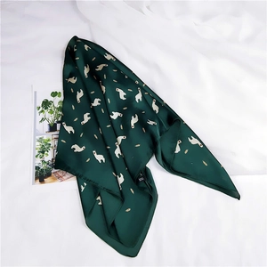 Détail d'un foulard en soie vert foncé avec motifs alpaga blancs sur tissu blanc