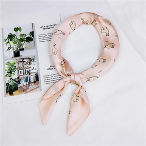 Détail d'un foulard en soie rose avec motifs alpagas noué en anneau sur un magazine