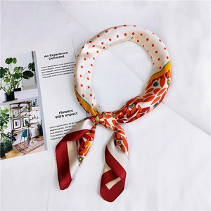 Détail d'un foulard en soie à fleurs et pois avec imprimé contrasté rouge, jaune et blanc