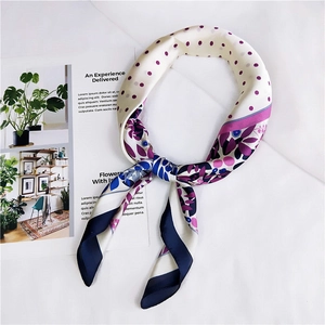 Détail d'un foulard en soie à fleurs et pois noué sur un magazine sous une lumière douce