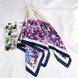 Vue détaillée d'un foulard en soie à fleurs et pois avec bordure bleue sur tissu blanc