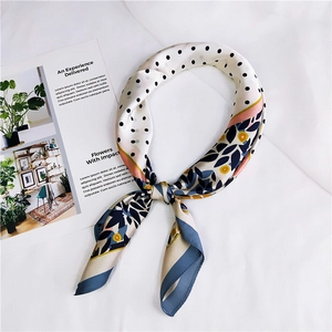 Gros plan détaillé du foulard en soie noué à motifs fleurs et pois sur fond blanc