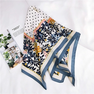 Détail d'un foulard en soie à motif floral et pois avec des feuilles bleues et fleurs jaunes