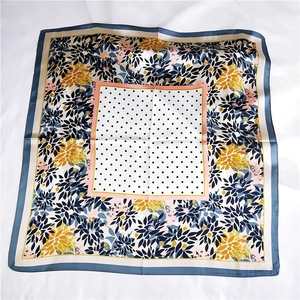 Détail d'un foulard en soie à fleurs et pois sur un fond blanc texturé doux