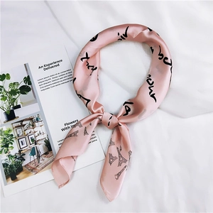 Detailed close-up of pink silk scarf with black Eiffel Tower print and elegant script lettering