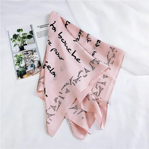 Close-up of pink silk square scarf with Eiffel Tower prints and elegant French script