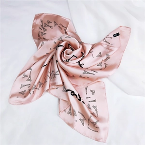 Macro detail of pink satin square scarf featuring Eiffel Tower print and elegant script