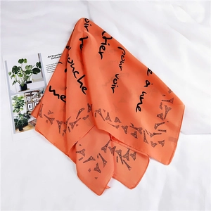 Detail of orange square silk scarf with French script and Eiffel Tower print texture
