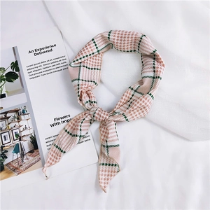 Detail of pink and green houndstooth pattern scarf on a white textured background