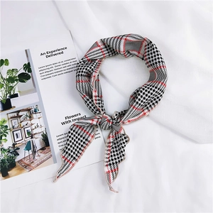 Detail of a chic houndstooth silk scarf with red accents and elegant knotted display