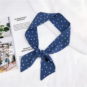 Gros plan d'un foulard en soie à pois bleu marine noué sur un fond stylé et élégant
