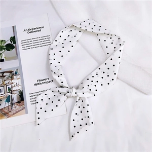 Détail d'un ruban en soie blanc à pois avec un nœud décoratif sur des magazines