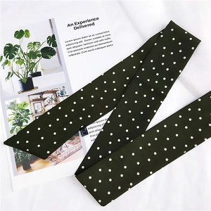 Détail d'un foulard en soie vert foncé à pois blancs avec étiquette et coutures lisses