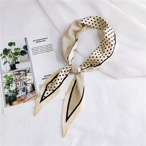 Close-up of a polka dot silk scarf tied in a bow on a white fabric background