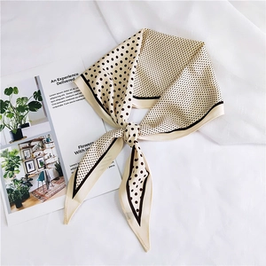 Close-up of knotted polka dot silk scarf with black contrast hem on textured background