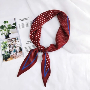 Close-up of wine red polka dot silk scarf with blue borders on white fabric