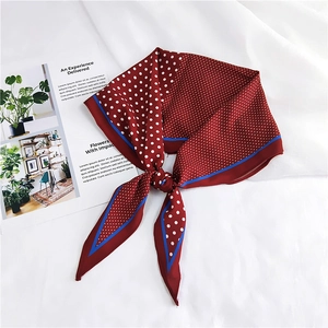 Close-up of a red polka dot silk scarf with blue edges folded on a white background