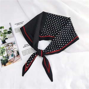 Close-up of silk-like polka dot neck scarf with red border tied in an elegant bow knot