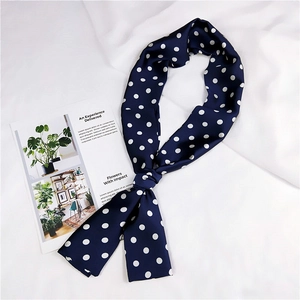 Dettaglio della lunga sciarpa di seta blu navy a pois bianchi su tessuto bianco
