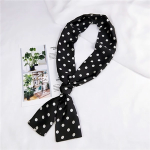 Dettaglio di un foulard stretto a pois bianchi e neri su uno sfondo bianco strutturato e curato