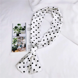 Primo piano di un foulard di seta lungo a pois bianchi e neri con finitura lucida