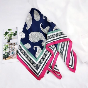Détail d'un foulard en soie à motif paisley avec des bords rose et vert sur tissu blanc
