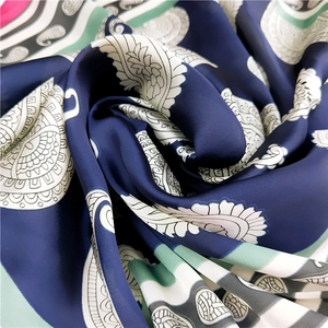 Gros plan détaillé d'un foulard en soie bleu marine avec motif paisley et fini satiné