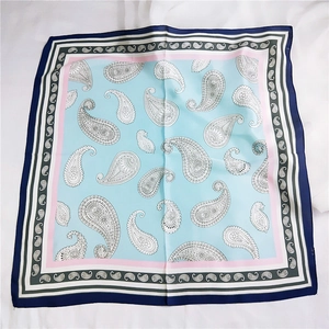 Vue à plat d'un foulard carré en soie aux motifs paisley bleu clair et bleu marine