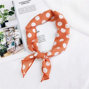 Close-up of vibrant orange silk scarf with white polka dots and stitched edge