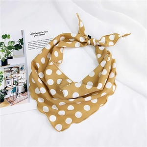 Detail of mustard yellow polka dot silk scarf with scalloped edges on white fabric