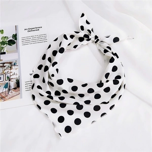 Detail shot of white silk scarf with black polka dots on soft textured fabric