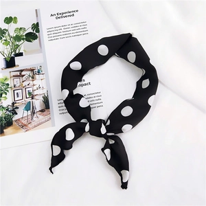 Close-up of a stylish black silk neckerchief with white polka dots tied in a chic knot