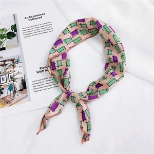 Detail of pink silk scarf with green and purple geometric grid pattern tied in a knot