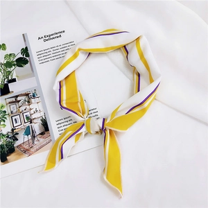 Detail of yellow and white striped silk scarf tied in a knot on a lifestyle magazine