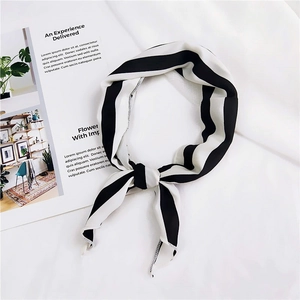 Flat lay of a classic black and white striped silk scarf with a stylish magazine background