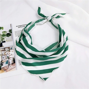 Detail showing green and white striped silk scarf knotted on a fashion magazine