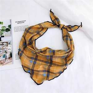 Detail of yellow plaid neckerchief with black rolled edges on a white fabric background