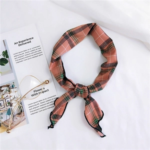Detailed view of a pink plaid narrow scarf with black stitched edges on a white background