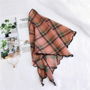 Detailed view of checkered triangle scarf with elegant scalloped wavy edges on white fabric