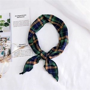 Close-up of green and blue plaid skinny silk scarf with glasses on a textured background