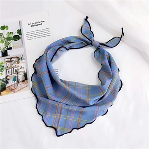 Detailed close-up of blue plaid silk scarf featuring delicate wave-stitched wavy edges