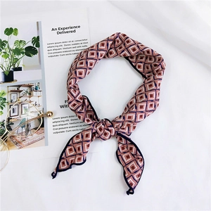 Detail of a knotted silk scarf with pink and navy rhombus print on white background