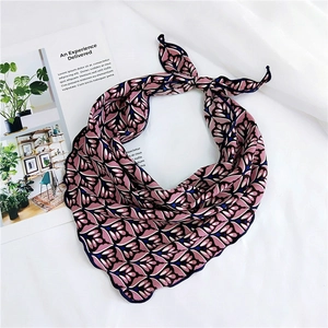 Detail of pink floral silk scarf with scalloped navy edges on a white backdrop