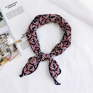 Detailed view of a pink and black floral pattern silk scarf tied in a neat loop