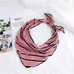 Macro detail of a knotted pink striped silk scarf on white fabric with a fashion magazine